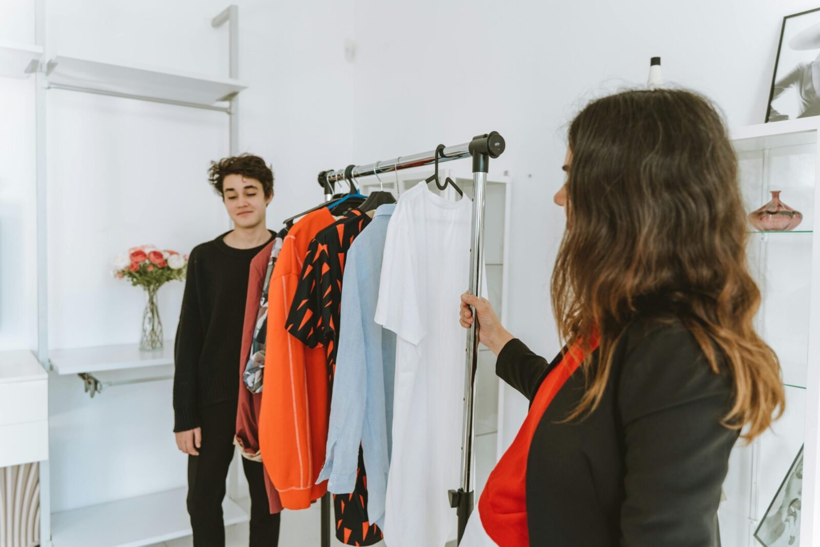 A mother and her teenage son shopping for clothes indoors, sharing a bonding moment.